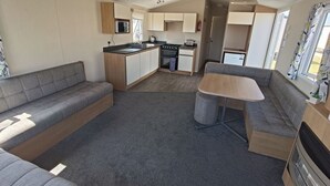 Interni di un camper compatto con angolo cottura, due zone relax e un piccolo tavolo da pranzo.