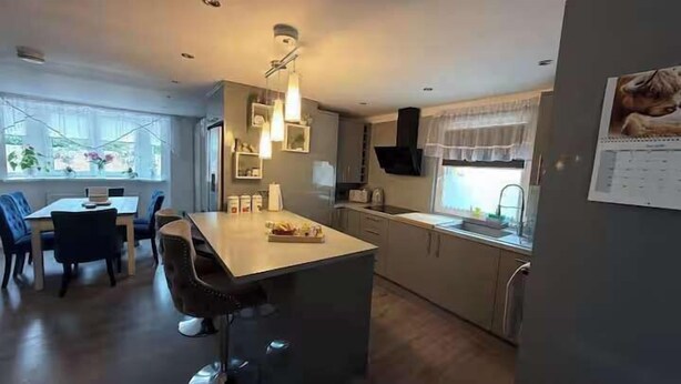 A modern kitchen with a central island, dining area with chairs, and a window providing natural light.
