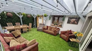 An indoor patio with artificial grass, a dining table with chairs, and a sofa.