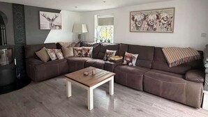 A modern living room with a brown leather sofa, a wooden coffee table, and decorative pillows.