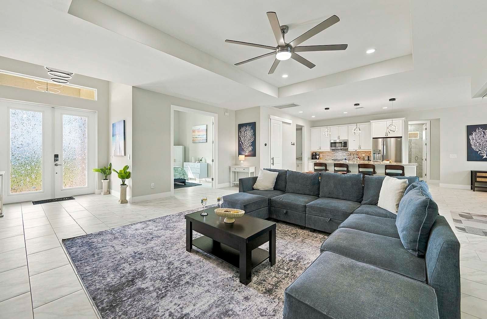 A spacious living room with a sectional sofa, a coffee table, and a ceiling fan.