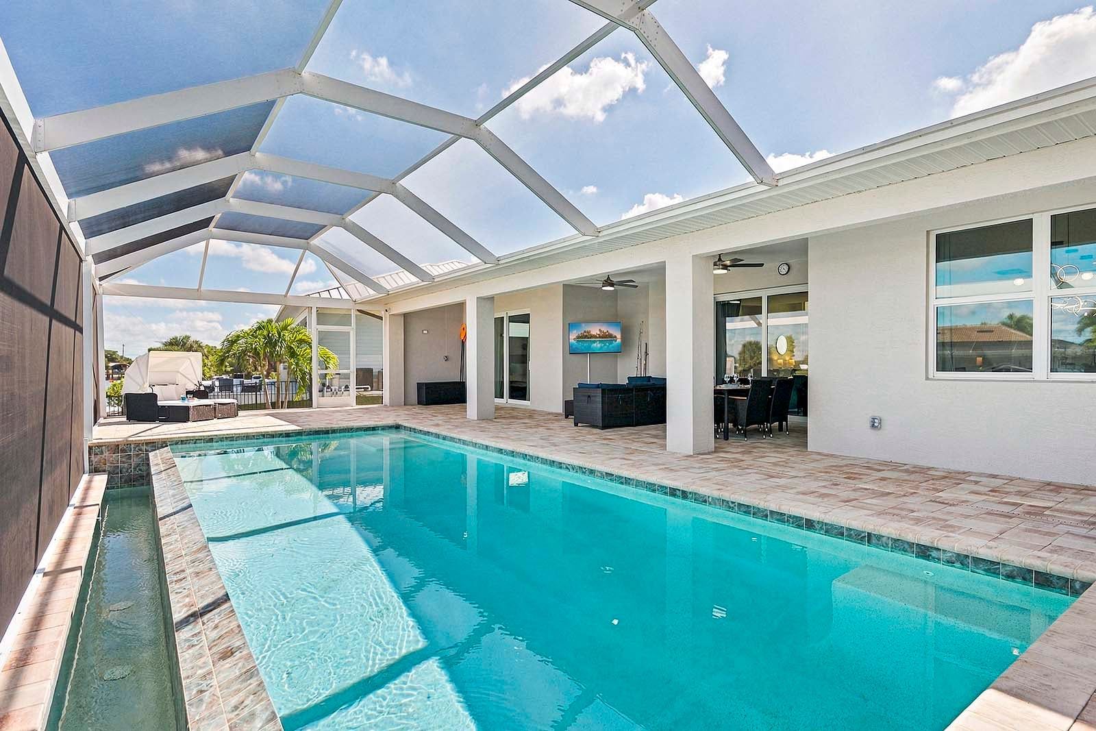 Piscina coberta com área de terraço, ventilador de teto e televisão.