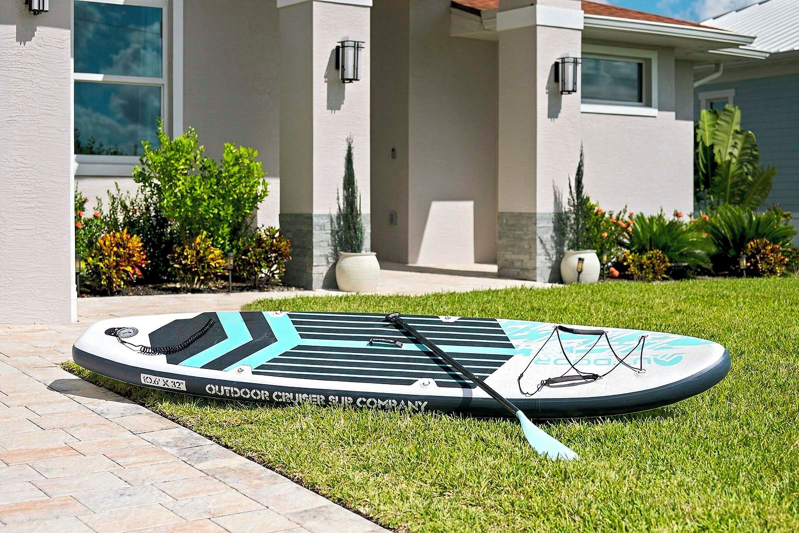 Ventilador de techo exterior con control remoto y un parasol a juego, situado en un césped frente a una casa.