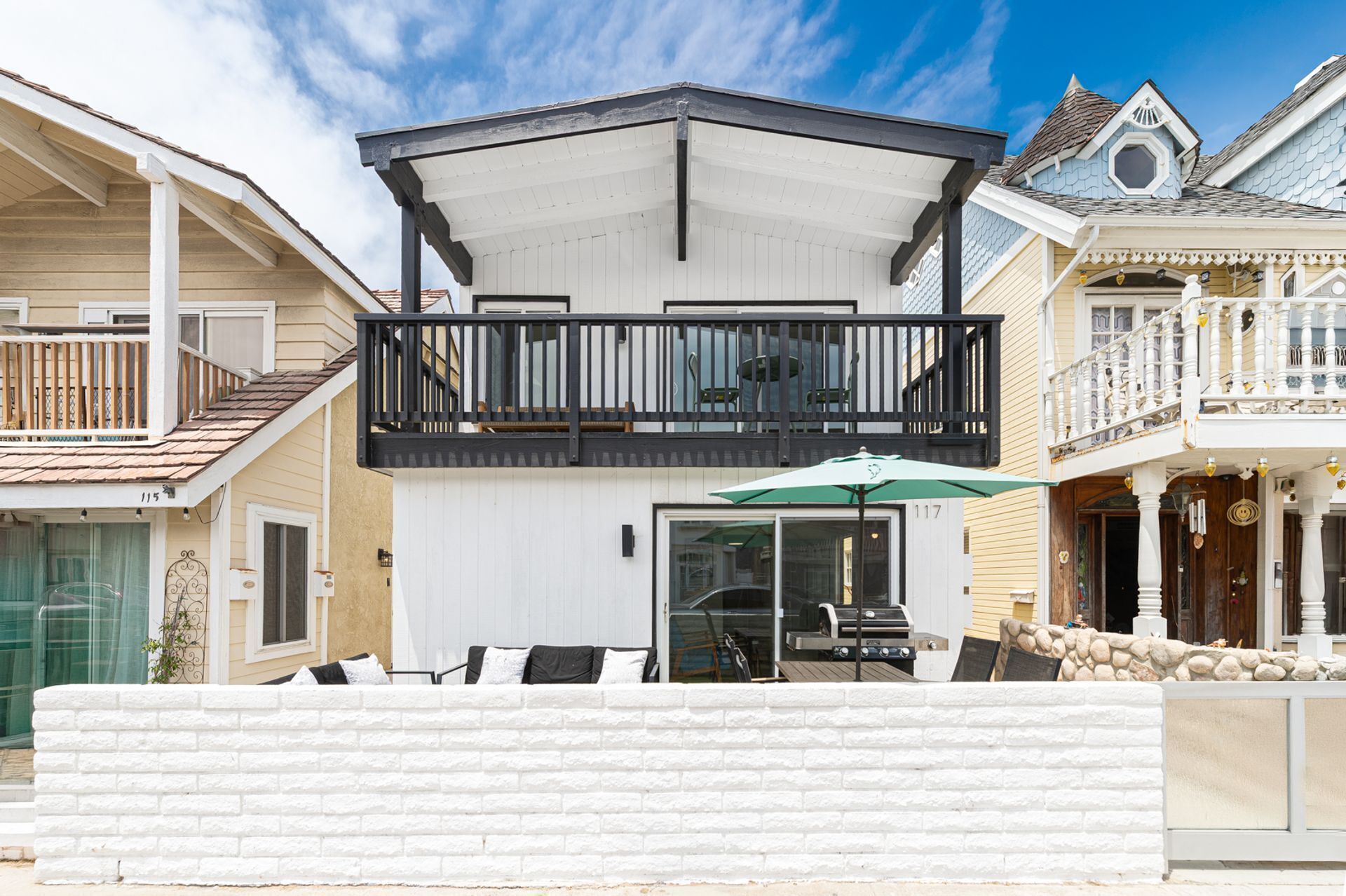 Une maison à deux étages avec un balcon, un garage et un mur en pierre.