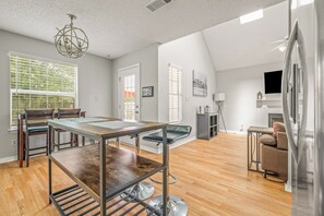Ein modernes Wohnzimmer mit Essbereich, Holzboden, einer Kristallleuchtre und einem Kamin.