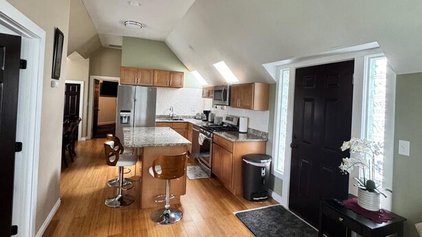 A spacious living area with a kitchen, a dining area, and a large window providing natural light. - Exclusive South Hill Apartment with AC in Puyallup (Puyallup)