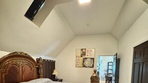 A bedroom with a large bed, a wooden headboard, a nightstand with a lamp, a decorative wooden pillar, and a ceiling light. - Exclusive South Hill Apartment with AC in Puyallup (Puyallup)