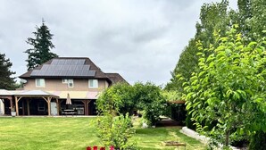A residential property with a well-maintained lawn, a house with a solar panel, and a garden with various plants and flowers. - Exclusive South Hill Apartment with AC in Puyallup (Puyallup)