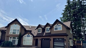 A two-story house with a large garage, a driveway, and a well-maintained lawn. - Exclusive South Hill Apartment with AC in Puyallup (Puyallup)