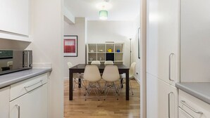 Une cuisine moderne avec un coin repas, un plancher en bois et des meubles de cuisine blancs.