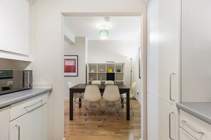 Eine moderne Küche mit Essbereich, Holzboden und weißen Schränken.