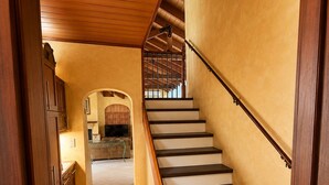 A staircase with wooden steps and a handrail, leading to a landing with a view of a kitchen area.