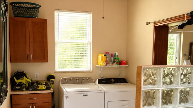 A laundry room with a washing machine, dryer, and a small bench.