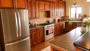 A kitchen with wooden cabinets, stainless steel appliances, a clock, and a window with natural light.