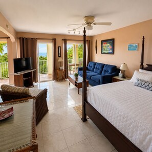 Una habitación de hotel con cama, televisor, balcón, sofá y ventilador de techo.