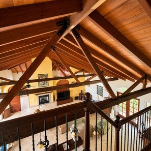 A spacious loft with exposed wooden beams, a fireplace, and a television in the living area.
