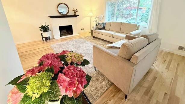 A living room with a sofa, a fireplace, a large window, and a floral arrangement. - Sunny Retreat with Stunning Golf Course Views (Centennial)