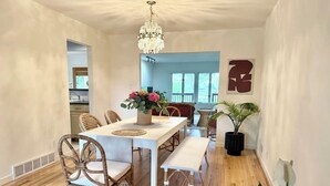 A dining area with a white table, wicker chairs, a bench, and a chandelier. - Sunny Retreat with Stunning Golf Course Views (Centennial)