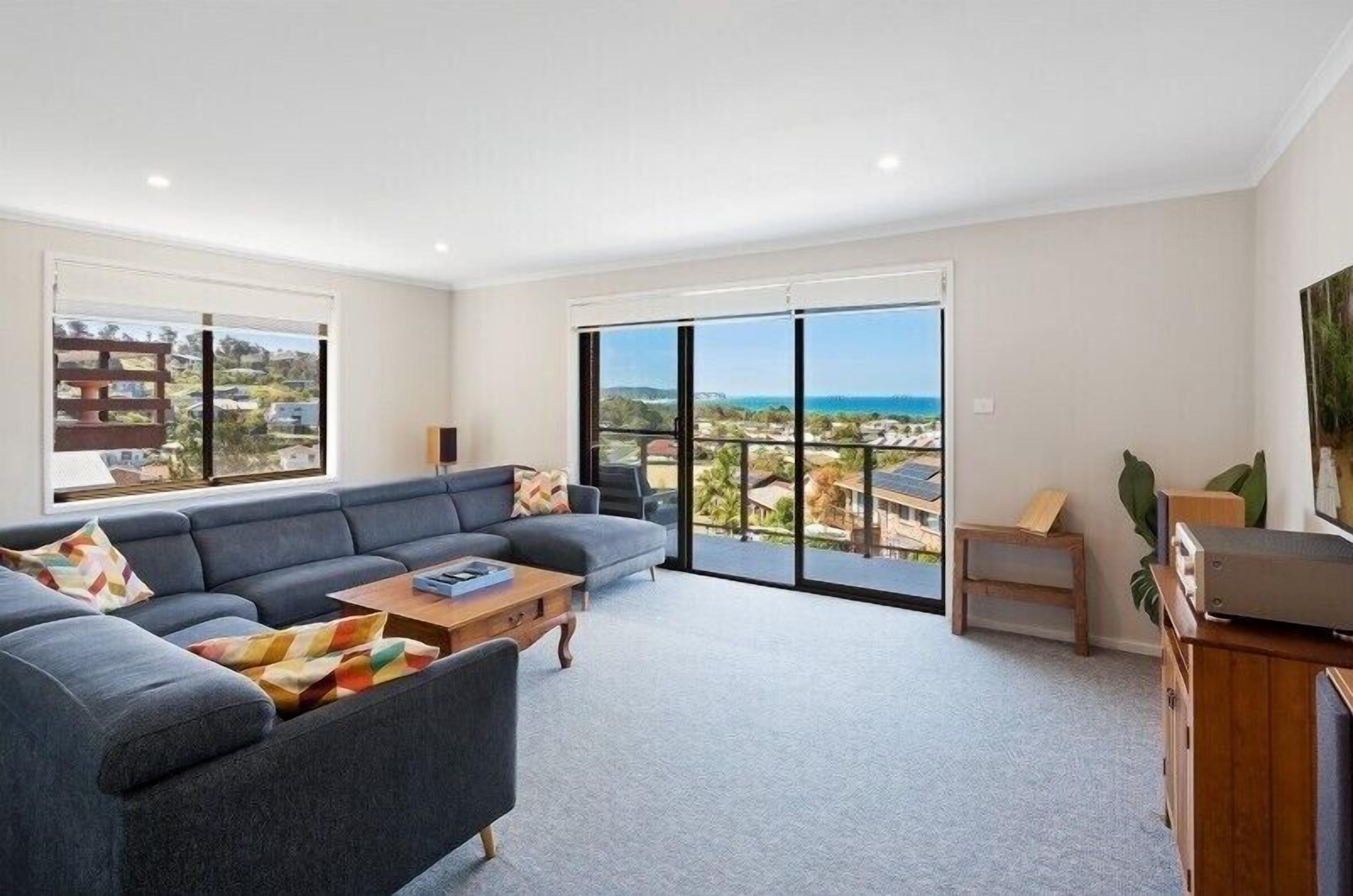 A spacious living room with a sectional sofa, a coffee table, and a view through large sliding glass doors.