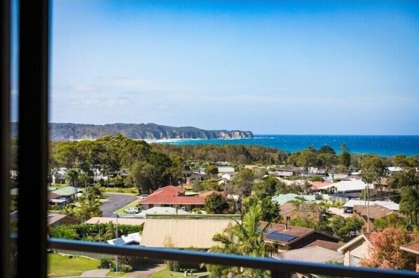 Zona residencial amb cases, vista a l'oceà i una serralada allunyada.