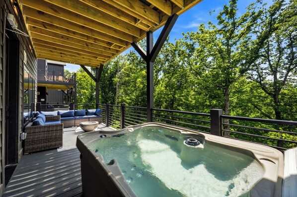 Een hottub onder een houten pergola met uitzicht op een weelderig groen bos.