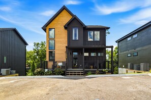 Een modern herenhuis met twee verdiepingen, een opvallend houten gedeelte aan de voorzijde, grote ramen en het zichtbare nummer '1325' op de zijkant.