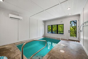 Ein Hallenbad mit freiem Blick auf Bäume durch große Fenster.
