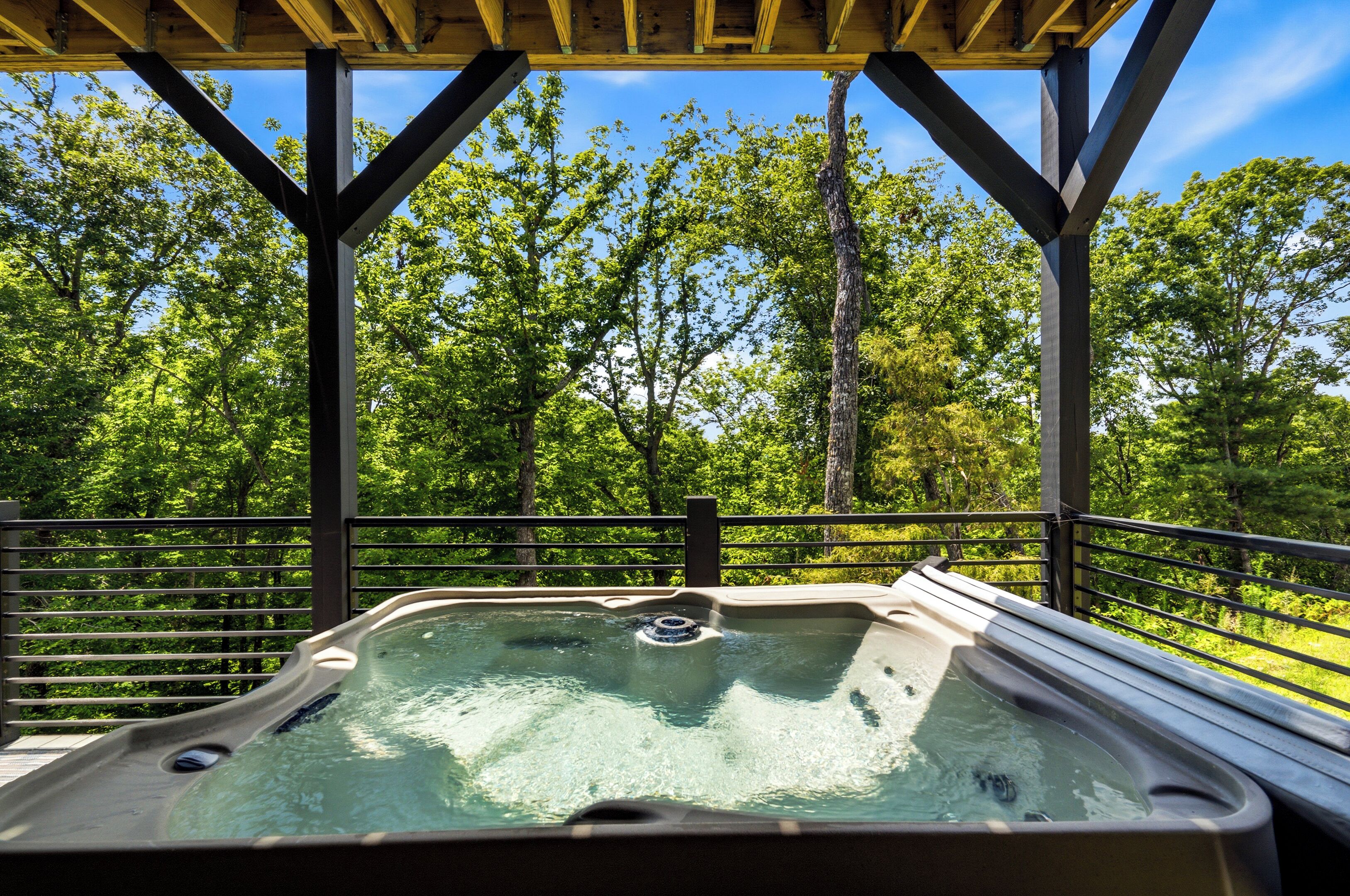 Ein Whirlpool unter einer Holzterrasse mit Blick auf einen Wald.