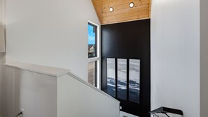 Een trap met een houten plafond en een zwarte muur met drie ingelijste foto's.