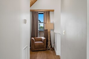Ein Zimmer mit einem braunen Ledersessel, einer Stehlampe und einem Fenster mit Vorhängen.