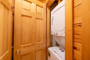 Eine Holztür, dahinter ein weißes Gerät, möglicherweise eine Waschmaschine, in einem Raum.