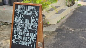 A cafe with a signboard listing various beverages.