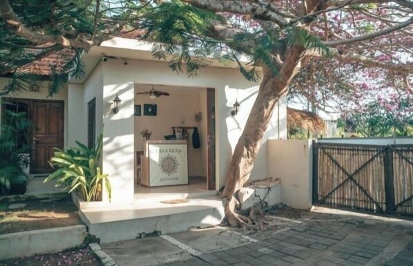 Una villa con un área de estar al aire libre techada, un portón y una planta en maceta.