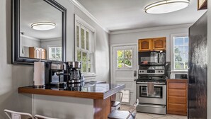 A kitchen with a central island, wooden cabinets, a stove, and a refrigerator. - East Hill Manor Large Double Apartment Villa (Pensacola)