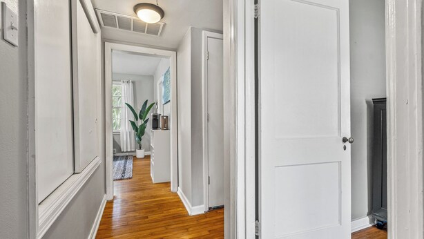 A hallway with white walls, wooden flooring, and a white door. - East Hill Manor Large Double Apartment Villa (Pensacola)
