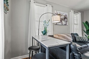 Una sala de estar con una mesa de mármol blanco, un sofá de cuero negro y una lámpara de pie.