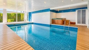A swimming pool with a wooden deck, a sauna, and a glass door leading outside. - A unique house in Roses, 975 m2, with an indoor pool and a 2,000 m2 garden (Roses)