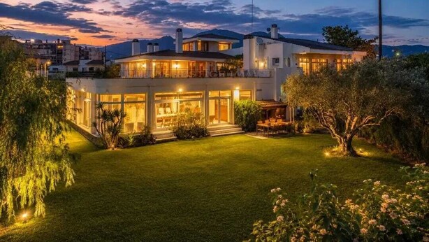 A modern house with a well-maintained lawn and a large tree in the foreground. - A unique house in Roses, 975 m2, with an indoor pool and a 2,000 m2 garden (Roses)