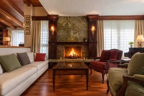 Ein Wohnzimmer mit Kamin, einer Couch, einem Sessel und einem Couchtisch.