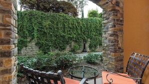 An outdoor patio with stone walls, a round table, and two chairs. - Vino Bello Resort - September 4 -7, 2026 (Napa)