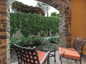 Eine Terrasse im Freien mit Steinmauern, einem runden Tisch und zwei Stühlen.