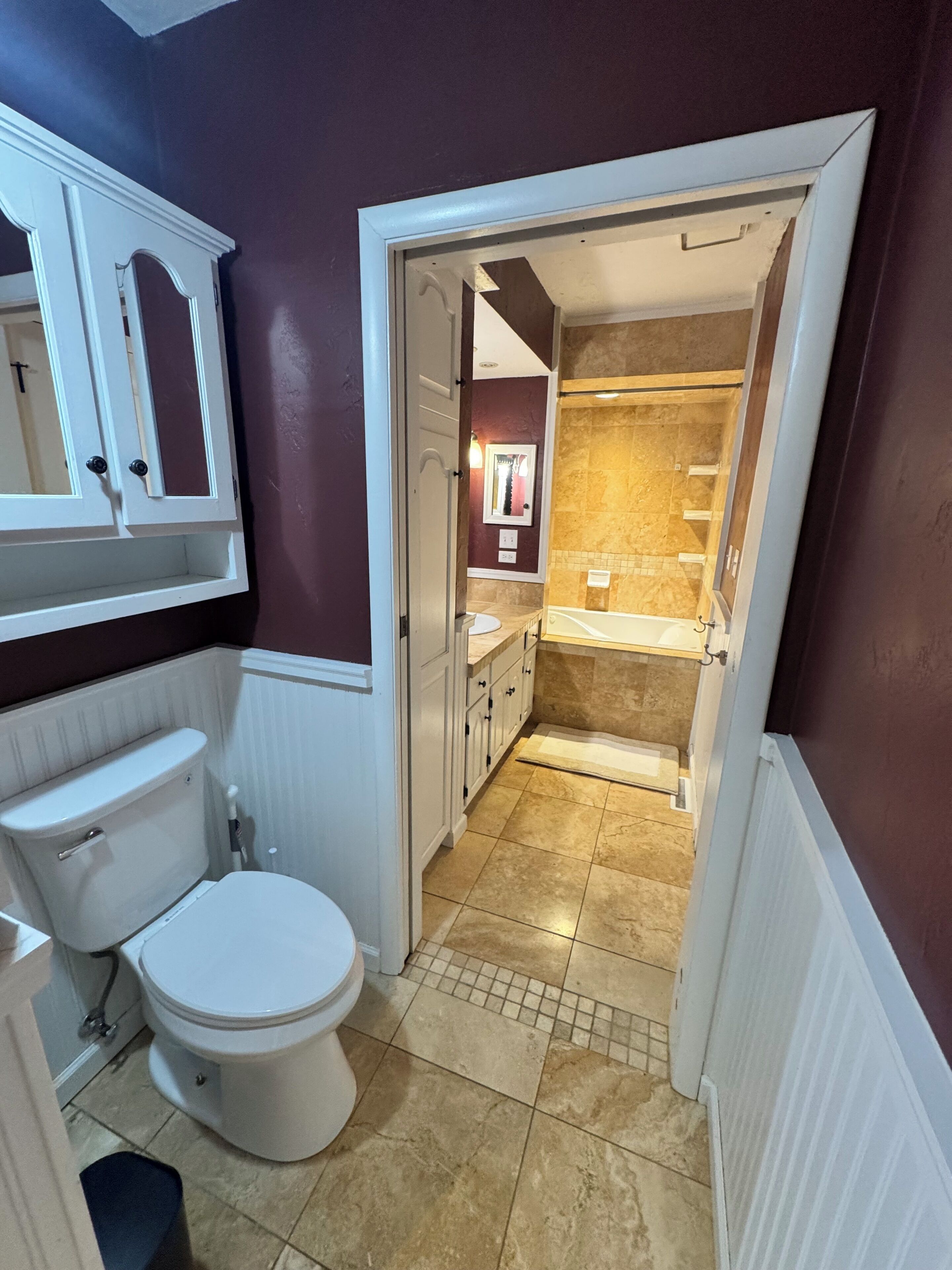 Une salle de bain comprenant des toilettes, un miroir et un espace douche.