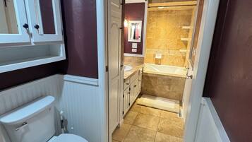 Une salle de bain comprenant des toilettes, un miroir et un espace douche.