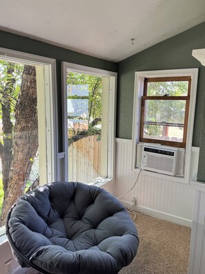 Une pièce dotée d’une grande fenêtre, d’une chaise et d’un climatiseur fixé au mur.