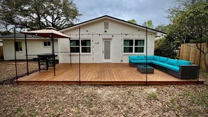 Ein Haus mit einer Holzdiele, einer überdachten Terrasse und einem blauen Modulsystem-Sofa.