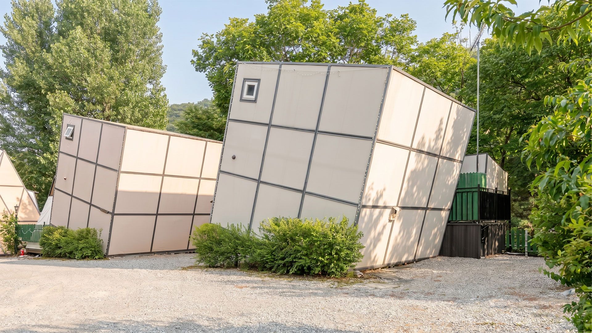 A building with a grid-like facade, surrounded by trees and a gravel path.