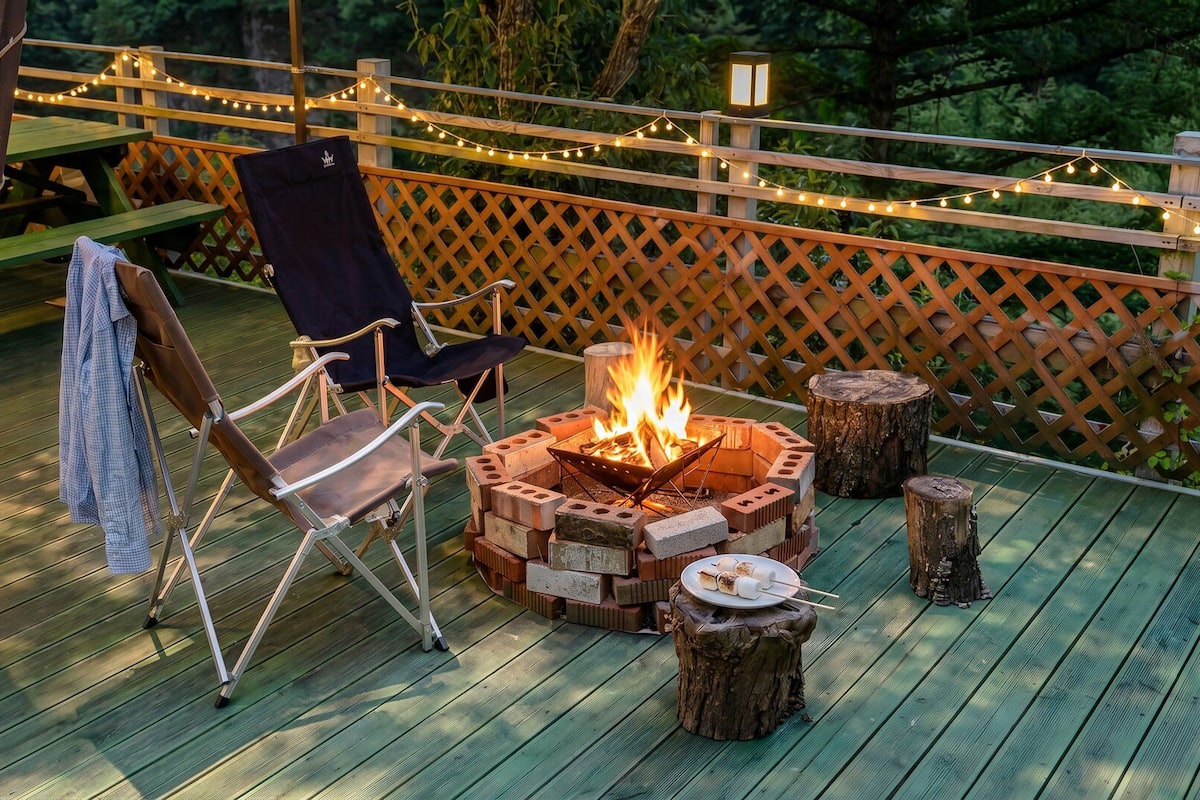 A deck with a fire pit, a folding chair, and a table with a blanket.