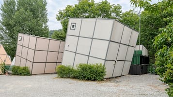 A building with a unique geometric facade, surrounded by greenery and a gravel ground.