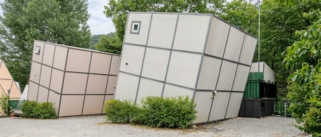 Un edificio con una fachada geométrica distintiva, rodeado de follaje y suelo de grava.