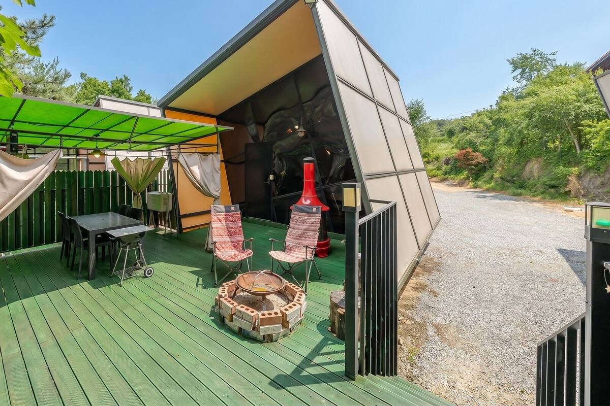 A covered outdoor area with a table and chairs, a barbecue grill, and a tent-like structure.